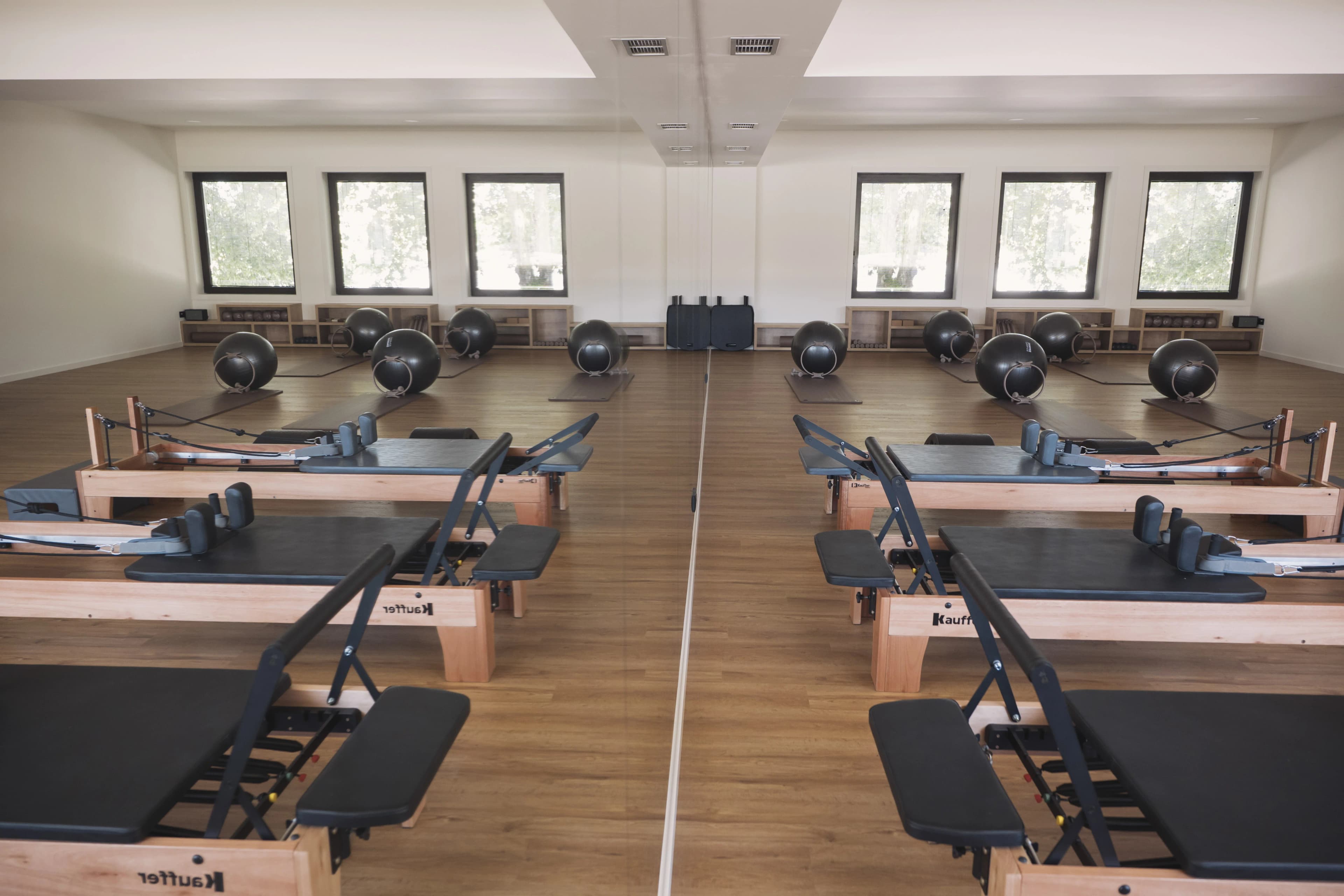 Sala de Pilates clínico com reformers e espelho.